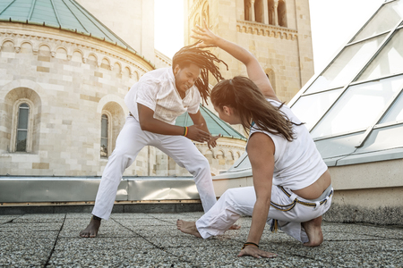 Young pair capoeira partners performing kicks outdoorの写真素材