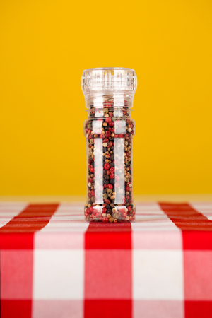 Colored Peppers Mix and pepper grinder in the kitchen table on yellow backgroundの写真素材