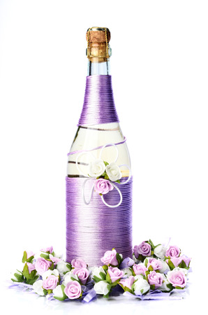 Decorated wedding bottle of champagne with roses, isolated on white backgroundの写真素材