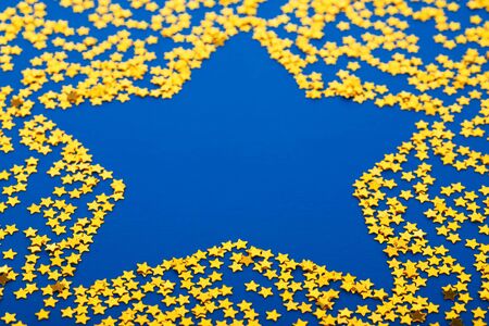 Golden glittering star shaped Christmas ornament isolated on blue backgroundの写真素材