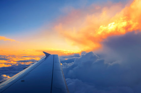 Wing of an airplane flying above the sunset clouds