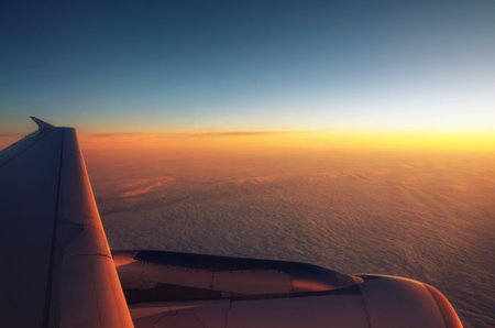 Fluffy clouds from the top and dramatic sunset, airplane view