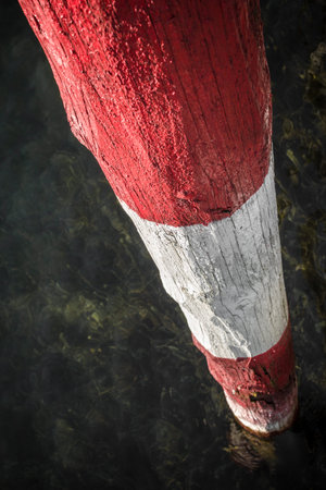 A wooden pole red and white, on the lakeside.の写真素材
