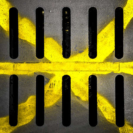 Detail of a manhole with yellow X drawn with paint spay.の写真素材