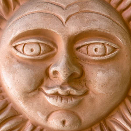 A clay sculpture depicting a smiling sun.の写真素材
