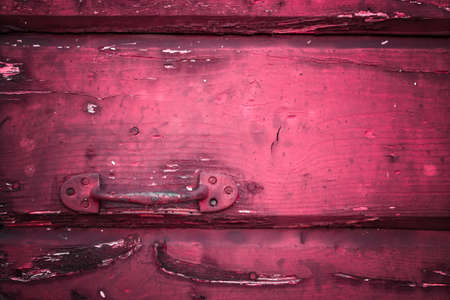 Close-up of a rusty handle on an old red door.の写真素材