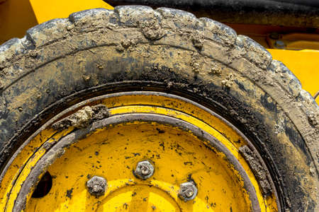 Extreme close up of tire bulldozer, yellow and covered with mud.の写真素材
