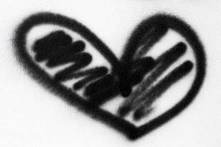 Black heart painted with spray paint on a white wall.の写真素材
