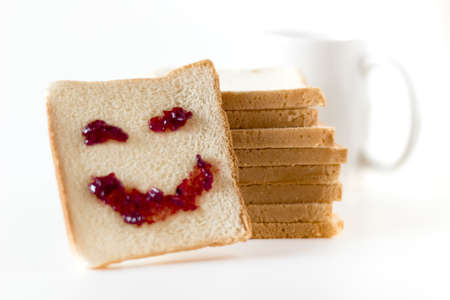 A smile at breakfast, made of strawberry jam, spread on a slice of bread.の写真素材