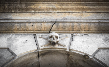 A stone skull placed near the entrance of a charnel house, in an Italian graveyard.