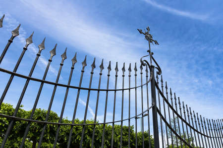 Wrought iron gate with cross against blue skyの写真素材