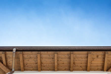 Rustic gutter with downpipe on the roof of a house.の写真素材