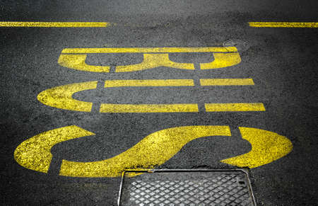 Yellow bus traffic sign painted on asphalt road.の写真素材