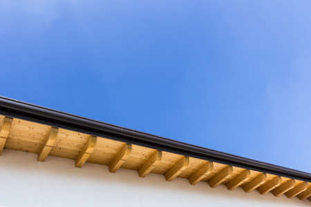 Low angle view of new house with wooden roof and gutter against clear blue skyの写真素材