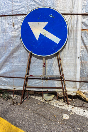 Old mandatory direction sign with scratches and dents in construction site.の写真素材