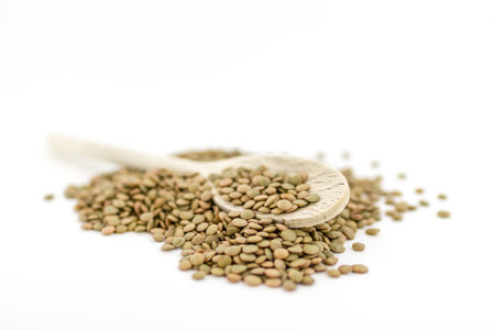 Natural organic dry lentils on white background with wooden spoon. Shallow depth of field.
