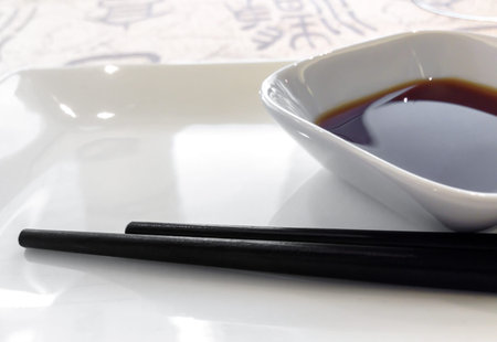 Soy sauce dish with a couple of chopsticks. Shallow depth of field. Defocused blurry background.の写真素材