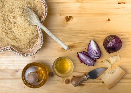 Ingredients for cooking an italian savory meal. Raw parboiled rice, onions, saffron and parmesan over rustic wooden background. Top view. Copy space.の写真素材