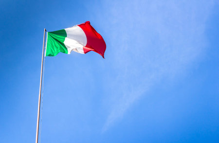 Waving Italian flag against blue skyの写真素材