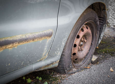 Close up of a vintage scrap car with rim and flat tyreの写真素材
