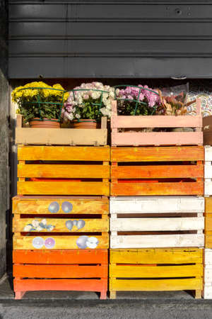 Colored wooden crates with flowers on top, from a florist. The rolling shutter is semi-closed.の写真素材