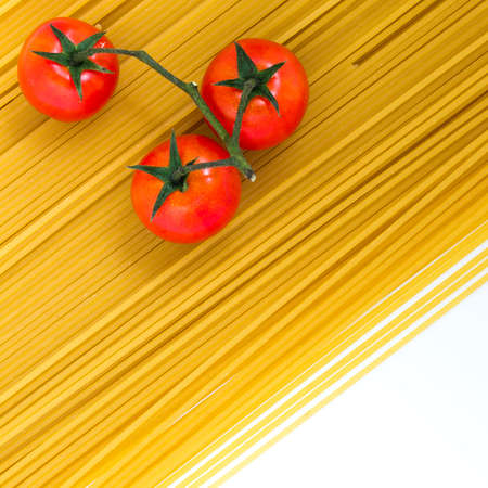 Spaghetti and cherry tomatoes isolated on white background. Uncooked Italian dried spaghetti. Flat lay. Copy space.の写真素材