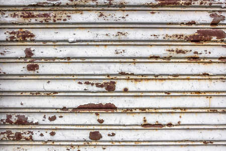 Old damaged white rolling steel door. A shutter totally rusted, closed by years.の写真素材