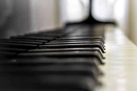 Old Piano keyboard with selective focus, behind a blurred background.の写真素材