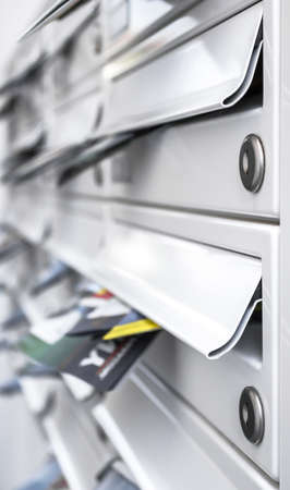 Modern metal mail boxes, full of leaflets. Ideal for concepts. Shallow depth of field.の写真素材
