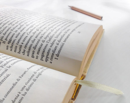 Close-up of a opened book on a white, table ready to be read and tell a story. Near, a wooden...
