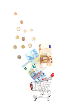 Shopping trolley cart with lot of many metal coins, and three banknote from fifty and twenty euro that coming out of the cart. Ideal for financial and business concepts.の写真素材