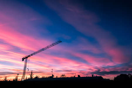 Construction crane silhouettes over amazing sunset skyの写真素材