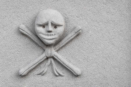 Skull and crossed bones carved on an new stone. Ideal for concepts, events and backgrounds. Space for text.の写真素材