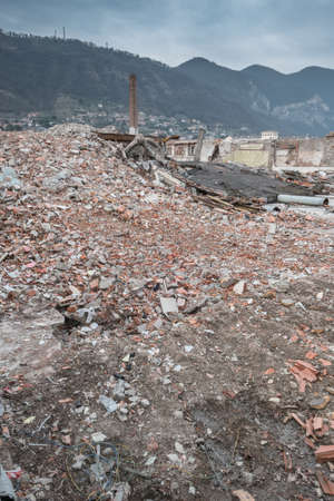 Demolition of buildings in urban environments. On background green mountains and a cloudy sky.の写真素材