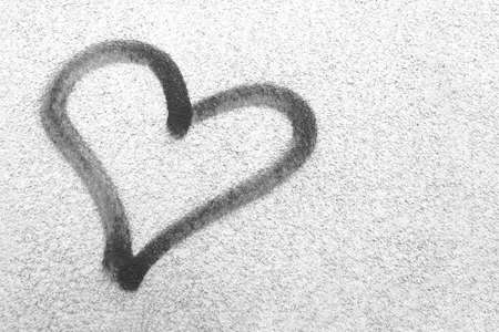 Concept or conceptual painted black abstract heart shape love symbol, dirty wall background, metaphor to urban and romantic valentine, grungy style.の写真素材