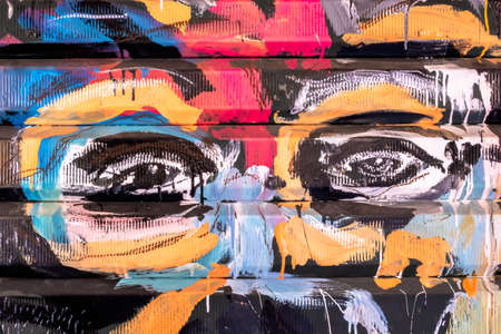 Graffiti with face of ethnic man on the old door of garage. Unknown artist. Bergamo, ITALY - May 06, 2019.のeditorial素材