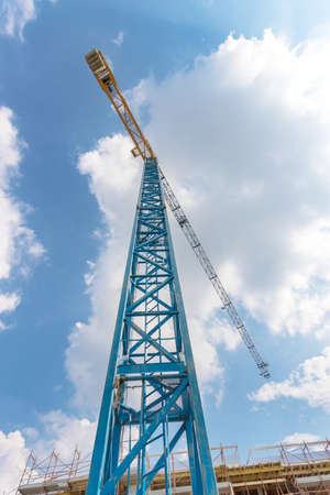 Rise building with cranes under construction. Building construction site against blue sky With clouds. Bottom view.の写真素材