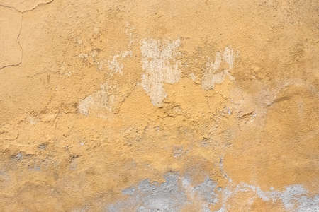 Grunge plaster wall with yellow scratched background. Old wall with peel swamp color stucco texture. Vintage wallpaper. Decay and cracks. Rough abstract surface.の写真素材