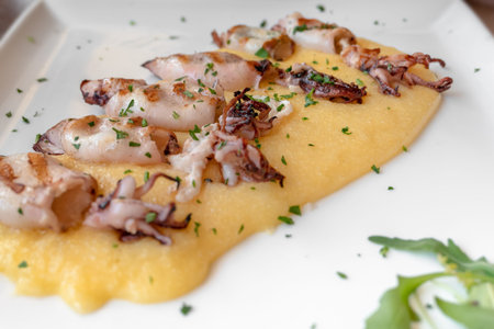 Grilled cuttlefish with polenta and salad. Typical italian fish dish of the upper Adriatic Sea....
