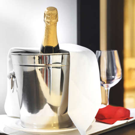 Champagne in ice bucket. Bottle of cold wine or champagne in ice bucket on white table at hotel room. Wedding reception, holiday concept.の写真素材