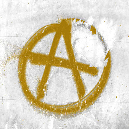 Golden symbol of anarchy painted on the peeling old wall. Ideal for textures, backgrounds and concepts.の写真素材