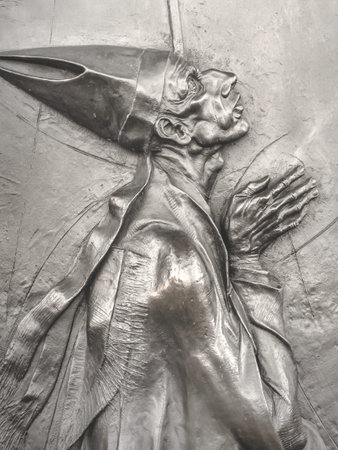 Bas-relief of an old pope in prayer on the bronze door of a church.