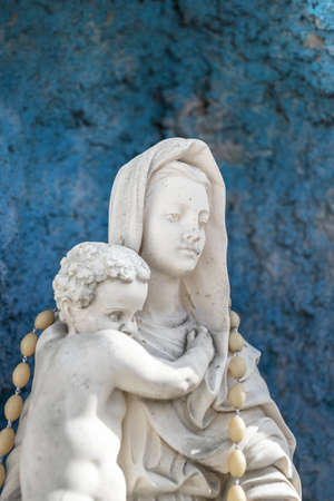 Statue of Our Lady of holy rosary and child Jesus. Blue rustic concrete on background.の写真素材