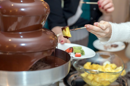 Vibrant chocolate fountain on wedding party. Chocolate fondue with fruits.の写真素材