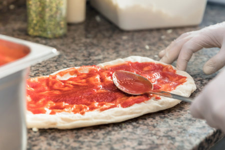 Fresh original Italian raw pizza, dough preparation in traditional style. Applying a tomato sauce.の写真素材