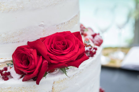 Wedding cake with two beautiful red roses. Wedding reception. Close-up.の写真素材