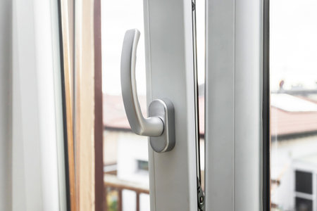 Aluminum window tilt and turn. Metal door frame closeup view. Sound isolation. Energy efficient, safety profile, blur garden outdoor background.の写真素材