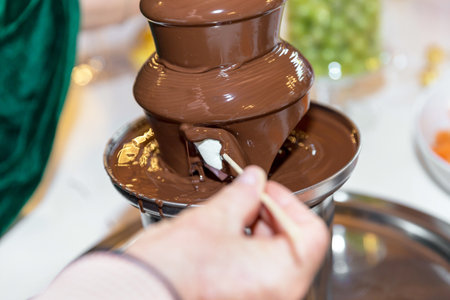 Chocolate fondue with fruits. Vibrant chocolate fountain on wedding party.の写真素材