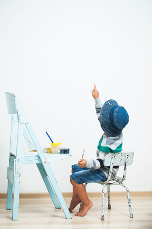 Happy child paints with paint. Wall for inscriptionの写真素材