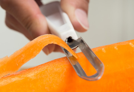 A woman's hand removes skin from carrotsの写真素材